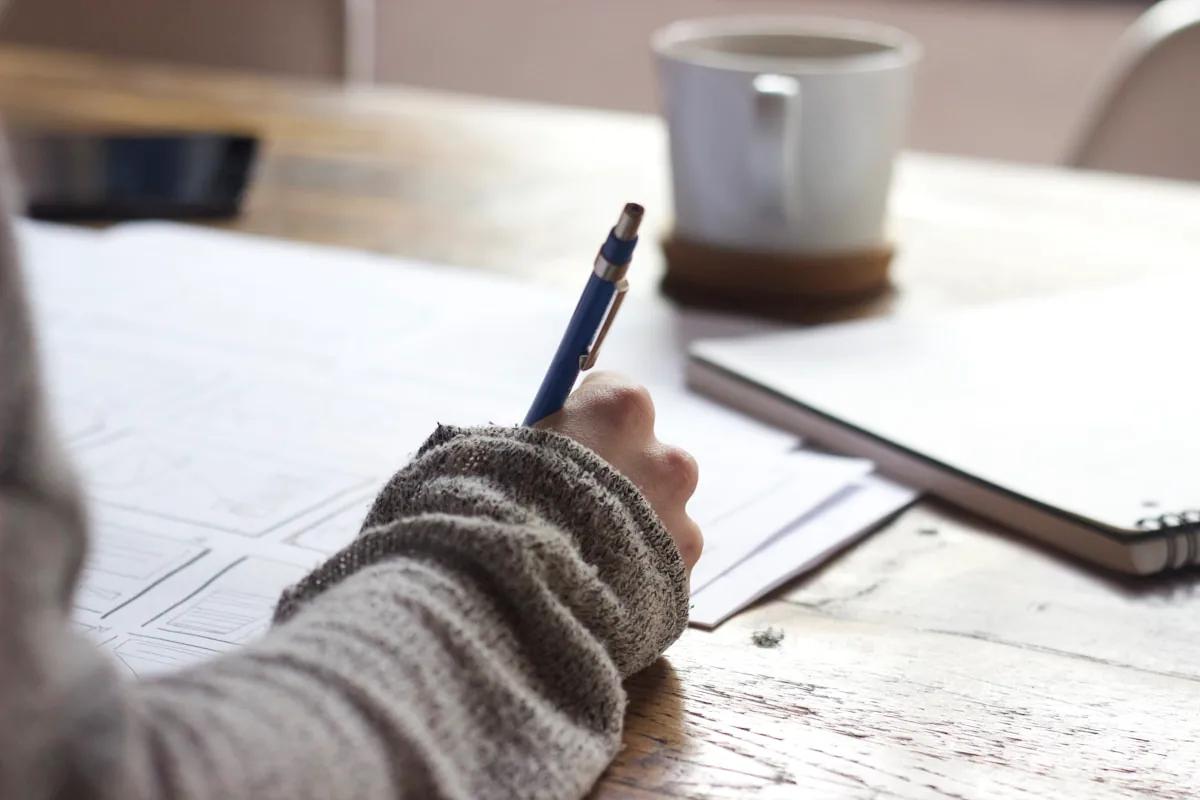 A person writing at a desk with papers — client red flags and knowing when to fire a client