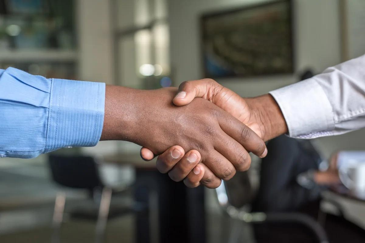 Handshake over a laptop — Freelancer.com bidding strategies that win projects